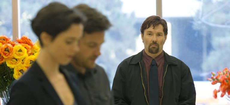 Rebecca Hall and Jason Bateman are watched by Joel Edgerton in The Gift (2015).