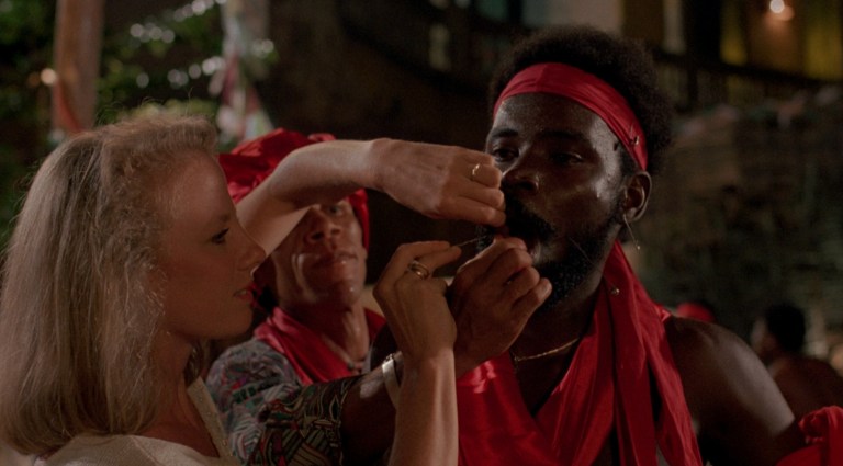 A woman pushing a needle into a man's cheek in The Serpent and the Rainbow (1988).