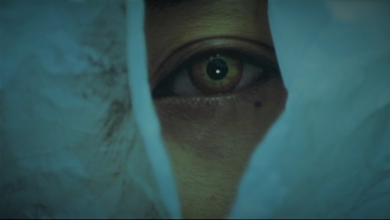 Tomie's eye opens from inside a plastic bag in Tomie (1998).