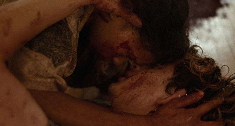 Maren and Lee embrace while covered in blood in Bones and All (2022).