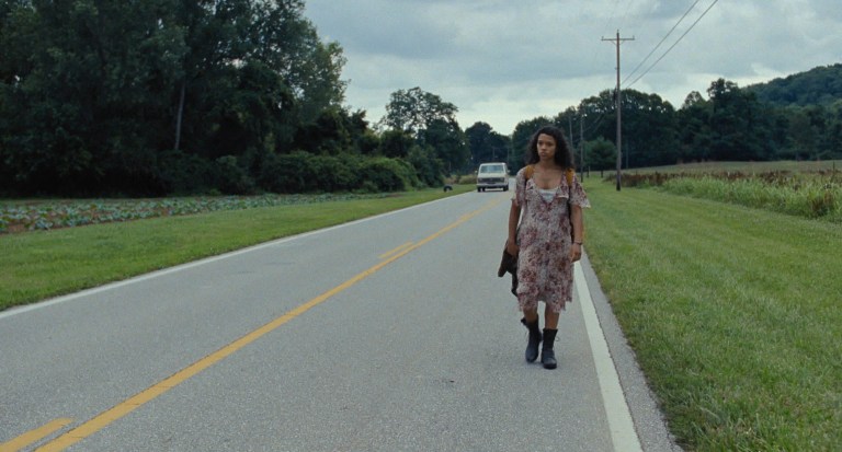 Maren walks alone on a road in Bones and All (2022).