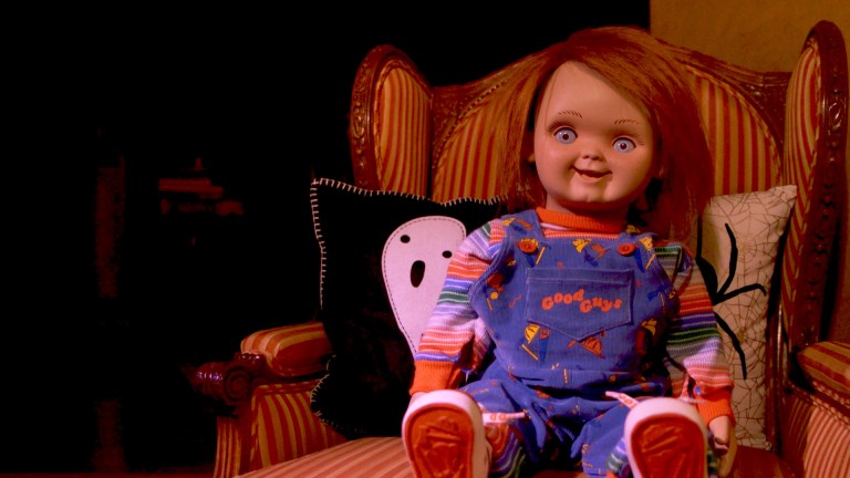 A Chucky doll sits in a chair in Living With Chucky (2022).