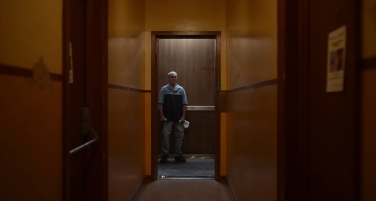 Joaquin Phoenix stands in an elevator in Beau is Afraid (2023).
