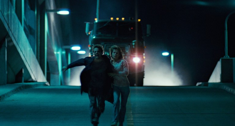 Kyle Reese and Sarah Connor run from a truck in The Terminator (1984).