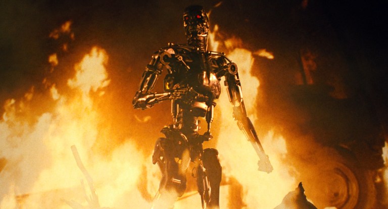 The T-800 endoskeleton stand among flames in The Terminator (1984).