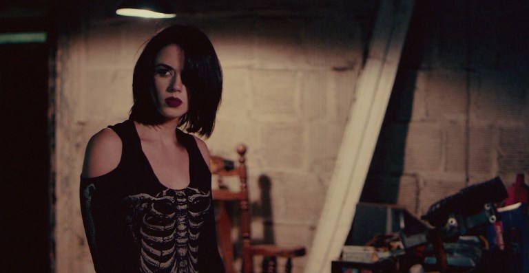 Tara Heyes (Jenna Kanell) walks alone through a dark building in Terrifier.