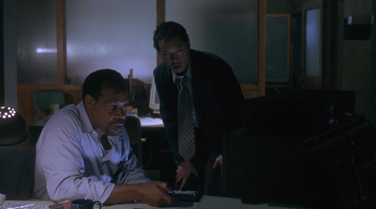 Detectives Tapp and Sing look at a Jigsaw tape in Saw (2004).