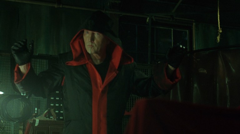 Jigsaw raises his hands in Saw (2004).