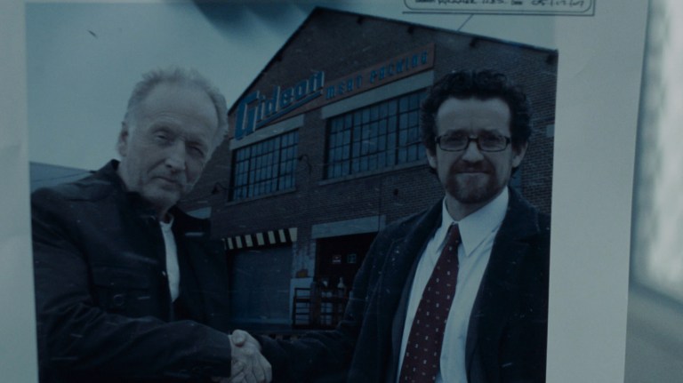 John Kramer and Art Blank shake hands in front of the Gideon Meat Packing plant in Saw IV (2007).