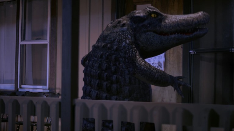 The alligator in Bad CGI Gator (2023) walks upright as it approaches a cabin door.