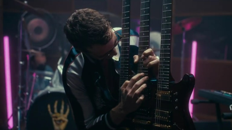 Jonah Ray playing a three-necked guitar in Destroy All Neighbors (2024).