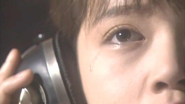 A young woman sheds a tear while listening to a song with headphones in "The Fearsome Melody."
