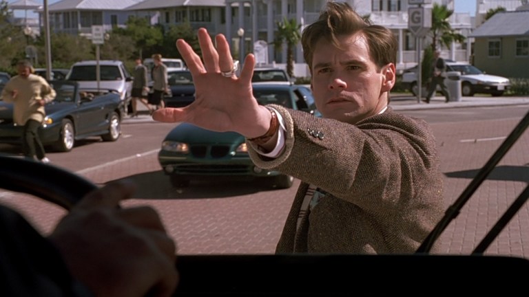Jim Carrey holds his hand up to stop a bus in The Truman Show (1998).