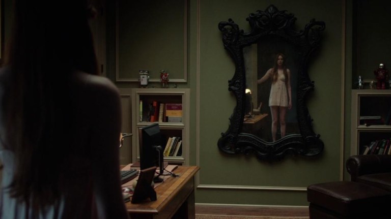 Karen Gillan stands in front of a haunted mirror in Oculus (2013).