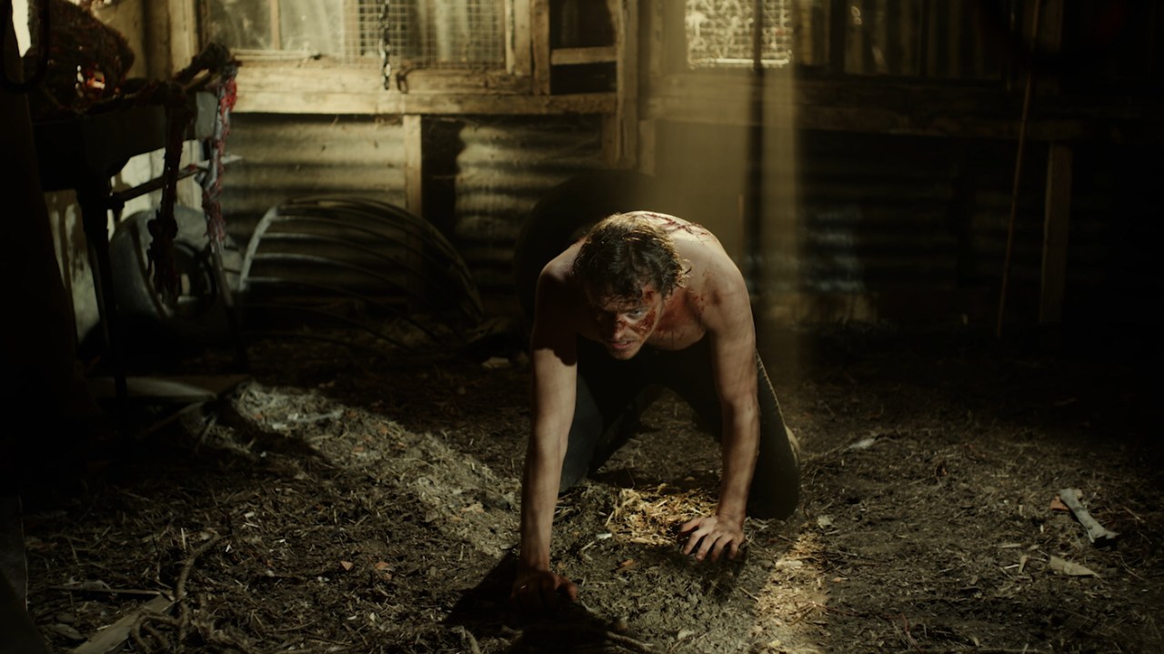 Christopher Robin tries to stand up after being tortured by Pooh in Winnie-the-Pooh: Blood and Honey.