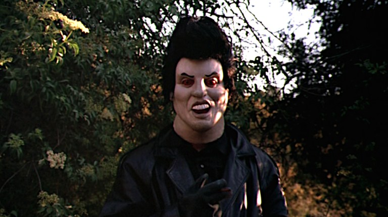 A person in a cartoonish Elvis mask as seen in The Backlot Murders (2002).