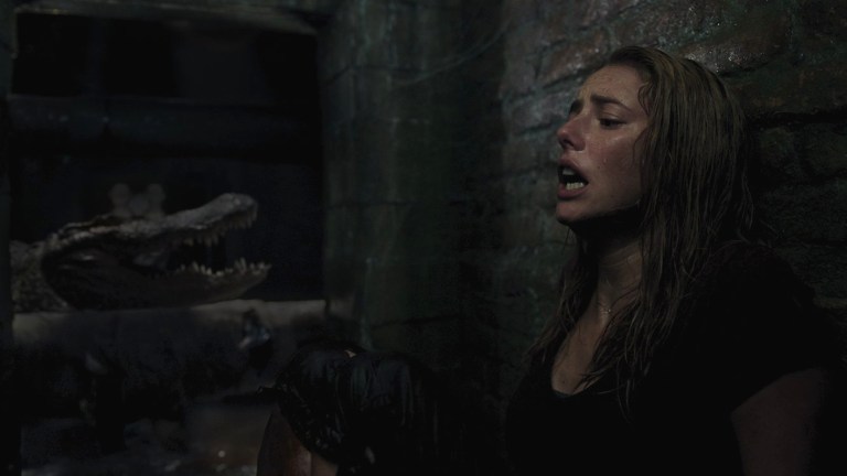 Kaya Scodelario in Crawl (2019) with an alligator passing by behind her.
