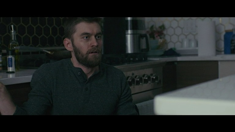 Matt is scared in a kitchen in Bag of Lies (2024).