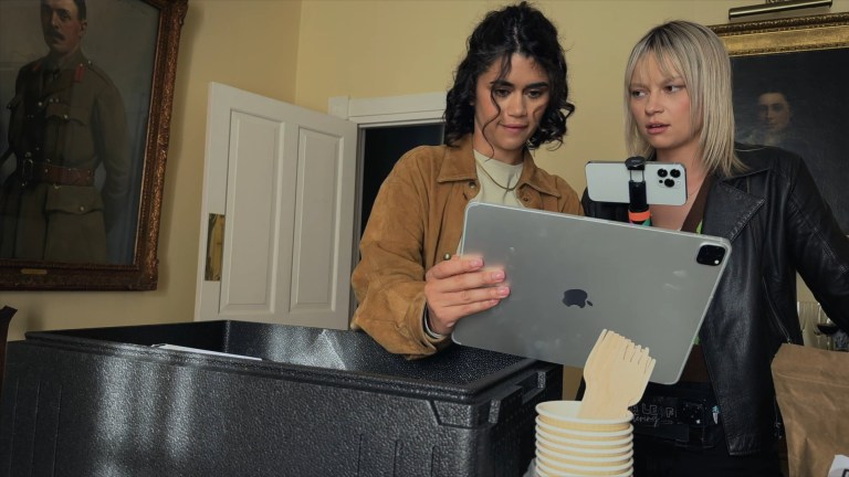 Louise watches video on a tablet while Thea looks skeptically at Louise in Dagr (2024).