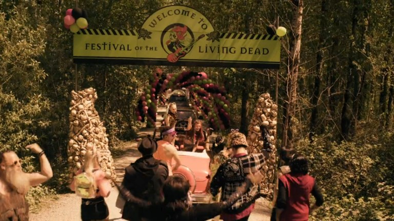 A crowd travels down a wooded path on their way to the Festival of the Living Dead.