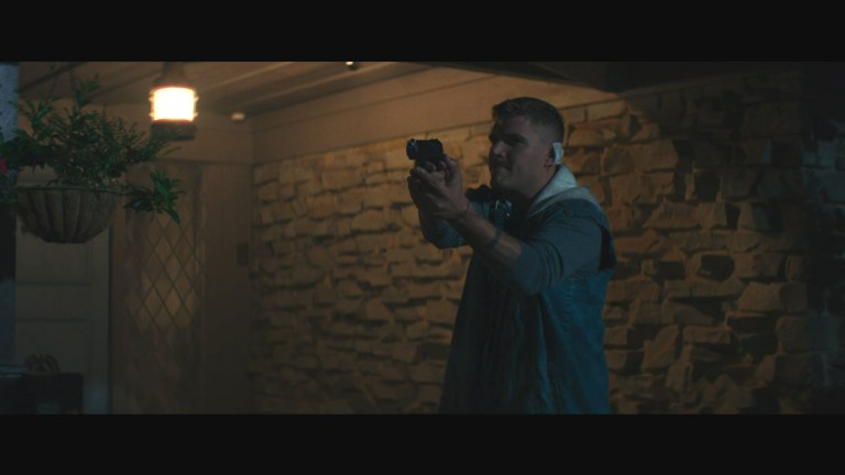 Thomas (Chris Zylka) points a gun in Model House (2024).