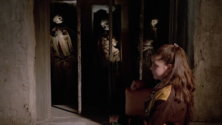 A young girl stands in front of a row of corpses in Poison for the Fairies (1986).