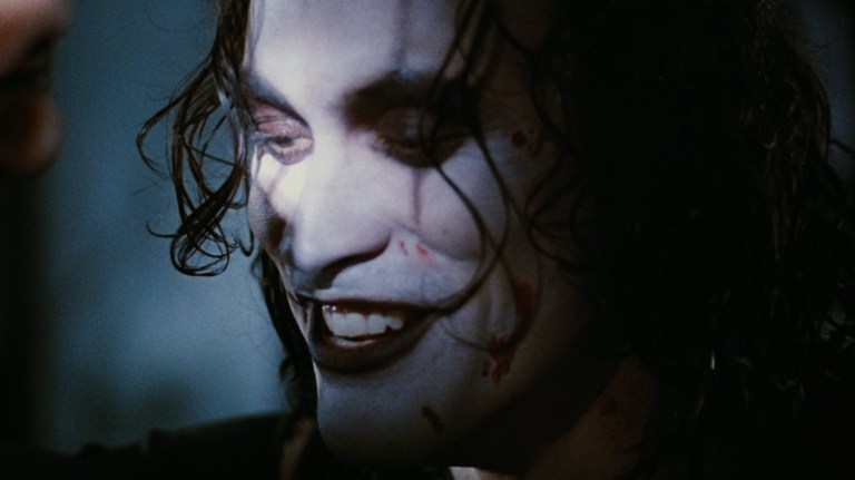 Eric smiles as a flashlight illuminates his face in The Crow (1994).