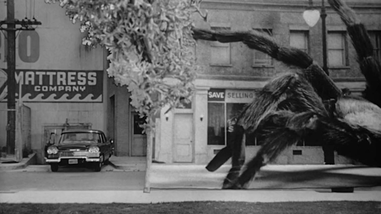 A giant spider approaches a car in Eart vs. The Spider (1958).