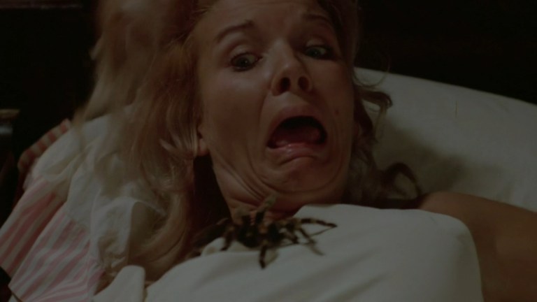 A woman looks horrified and disgusted as a tarantula on her chest crawls toward her face in Kiss of the Tarantula (1975).