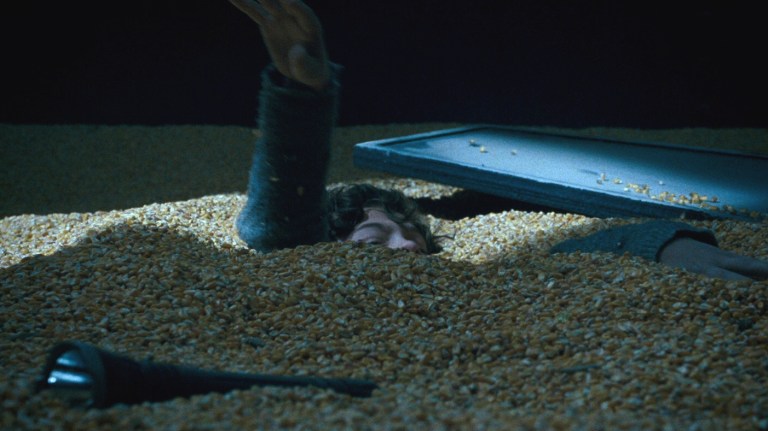 Marcus struggles to stay afloat in a silo filled with corn in A Quiet Place (2018).