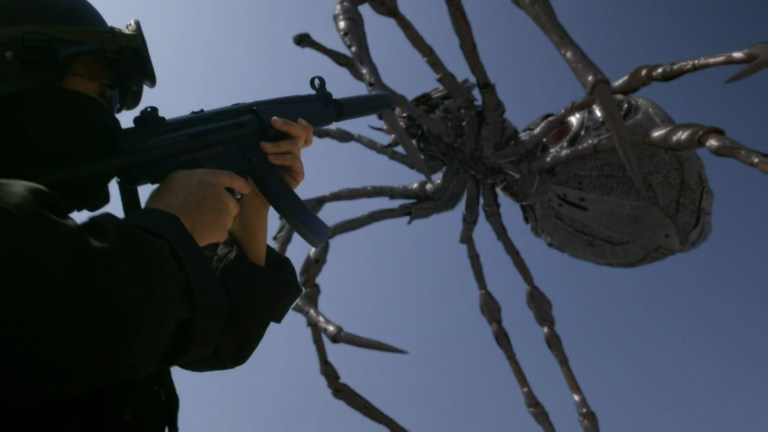 A large spider leaps over a person with a gun in Big Ass Spider (2013).