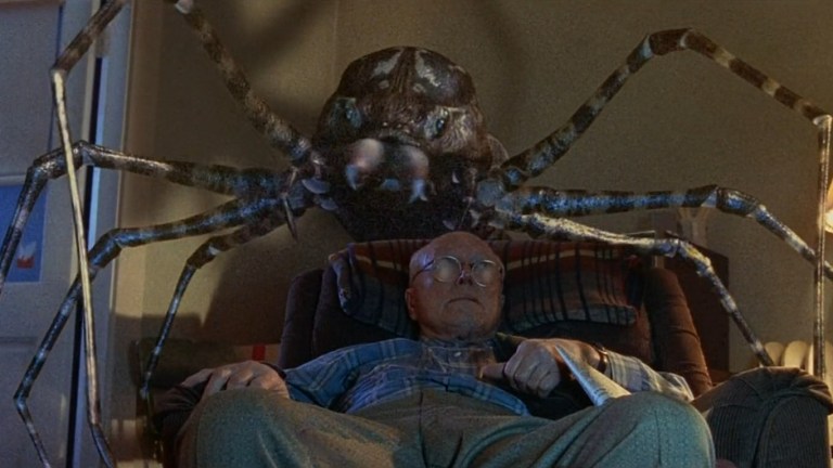 A giant spider sneaks up on a man sitting in a comfy chair in Eight Legged Freaks (2002).
