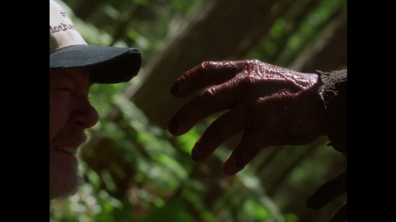 Johnny reaches a hand towards a victim in In a Violent Nature (2024).