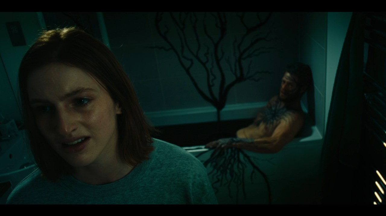 Dakota looks away while Axel sits, infected, in a bathtub in Kill Your Lover (2023).