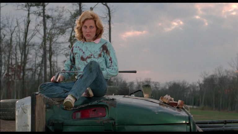 Victoria Scott holds a golf club while sitting atop a van in Blades (1988).