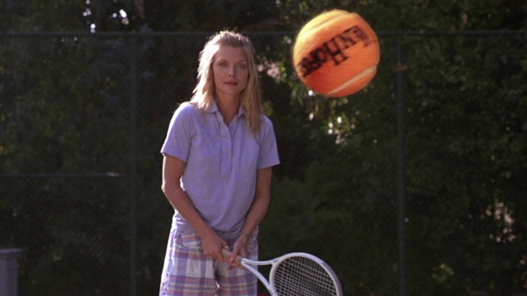 Michelle Pfeiffer looks at a tennis ba;ll in The Witches of Eastwick (1987).