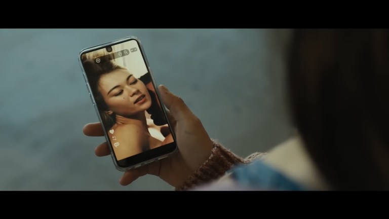 Iris looks at a deepfake image of herself in Afraid (2024).