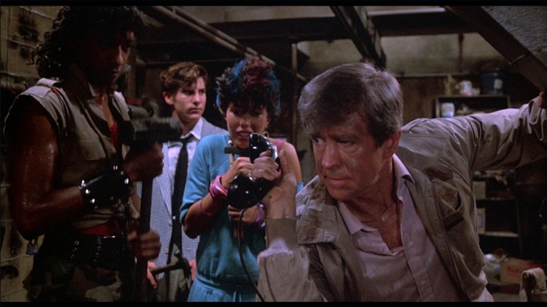 Burt holds up the phone so the punks can hear screaming in The Return of the Living Dead (1985).