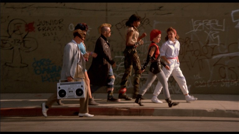 The punks walk down the sidewalk in The Return of the Living Dead (1985).