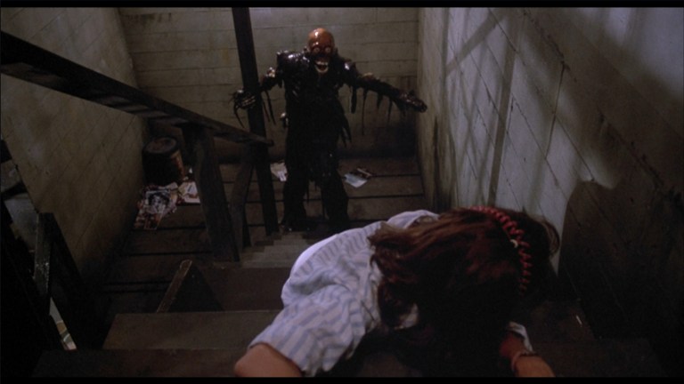 The Tarman climbs stairs towards Tina in The Return of the Living Dead (1985).