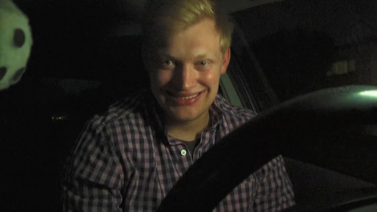 Milk smiles while sitting in his car in Milk & Serial (2024).