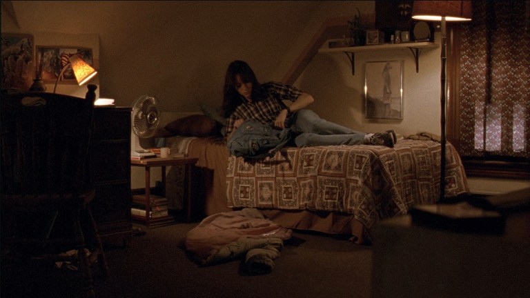 Samantha digs through her backpack while on her bed in The House of the Devil (2009).