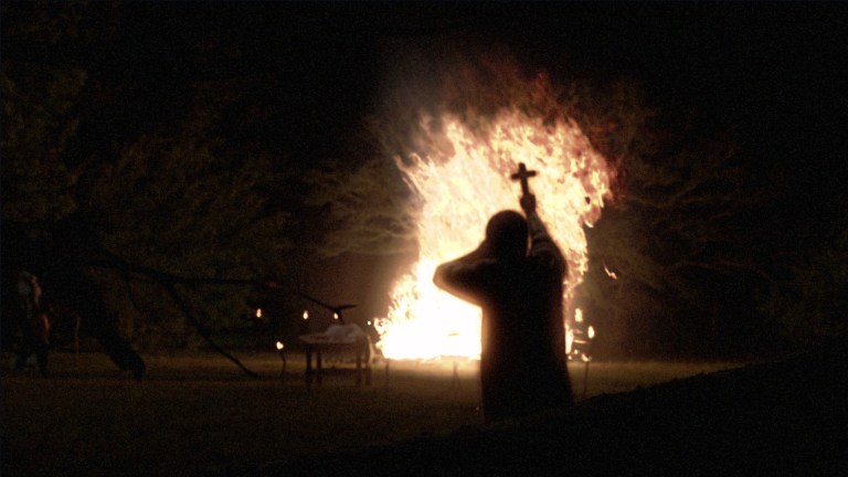 Cotton Marcus walks towards a fire in The Last Exorcism (2010).