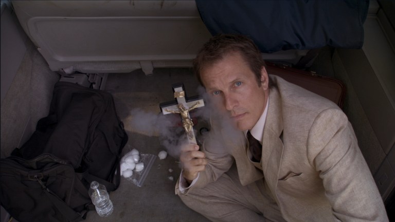 Cotton Marcus poses with a smoking cross in The Last Exorcism (2010).