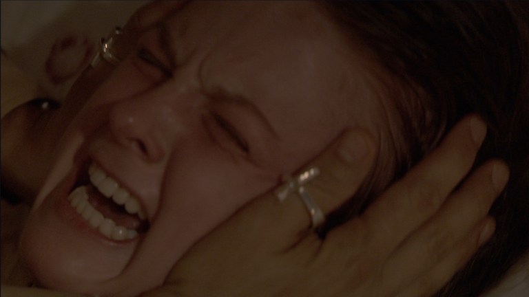 Reverend Marcus places his hands on Nell's head as she screams in The Last Exorcism (2010).