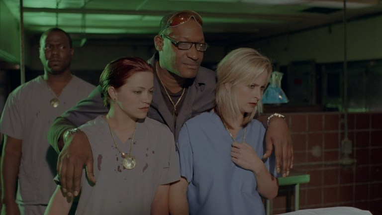Tony Todd with it arms on Raelyn Hennessee and Melissa Searing's shoulders in Cutter's Club (2025).
