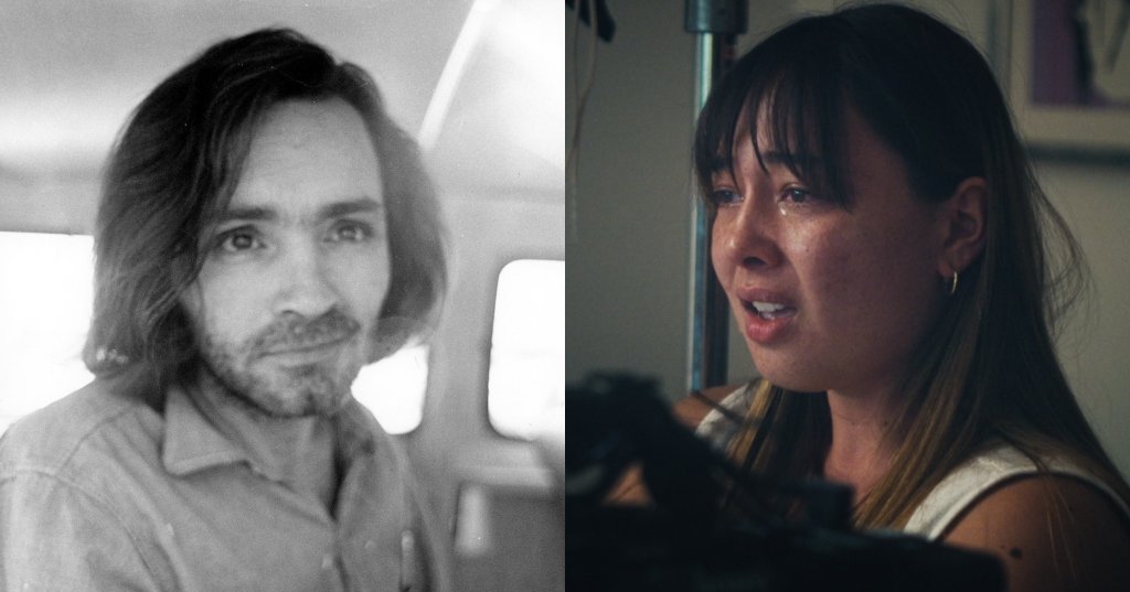Black-and-white photo of a long-haired, bearded man in a button-up shirt sitting inside a police van, looking at the camera.