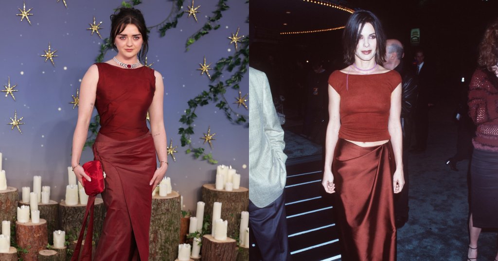 Maisie Williams in a custom burgundy sleeveless gown with a train, holding a red clutch, posing at a premiere event with candles and gold star decorations.