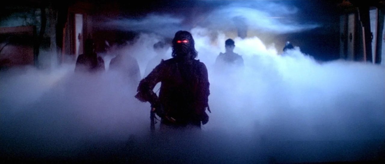 A dark silhouetted figure with red glowing eyes and a weapon stands in a corridor engulfed in thick white fog, with shadowy figures behind.