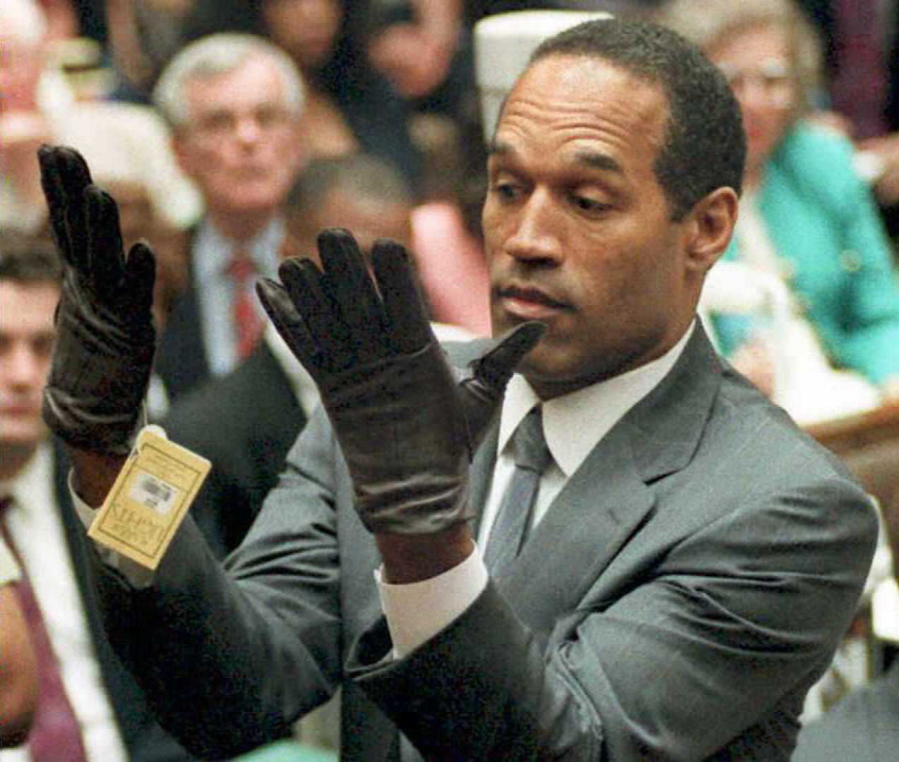 O.J. Simpson trying on a pair of large gloves in a Los Angeles courtroom during his 1995 murder trial